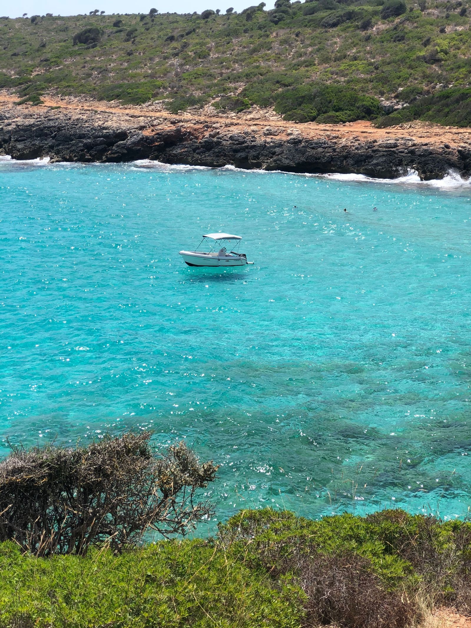 A small boat crossing turquoise water off Mallorca